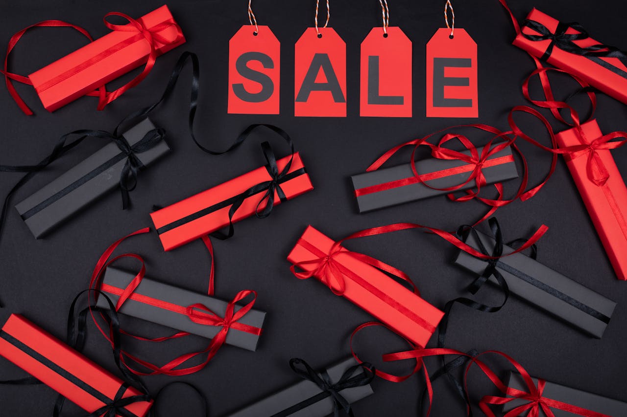 Red and black gift boxes with sale tags on black background, perfect for promotions.