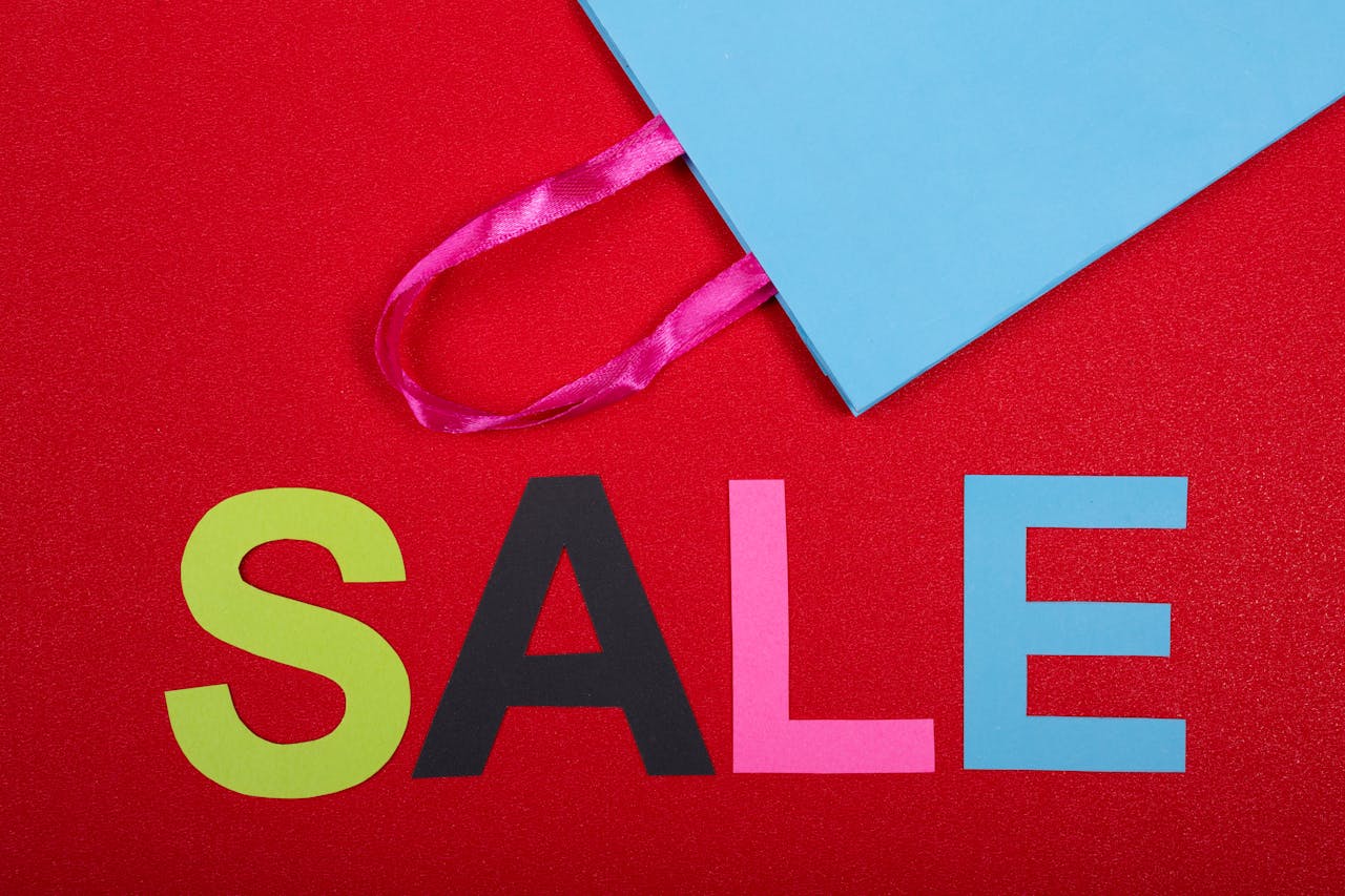 Vibrant shopping sale design with colorful letters and blue bag against a red backdrop.